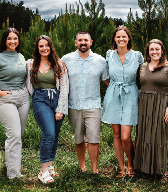 Group of five chiropractors standing in a green outdoor setting, smiling and dressed in casual attire, promoting Foundation Family Chiropractic's community-focused wellness services.