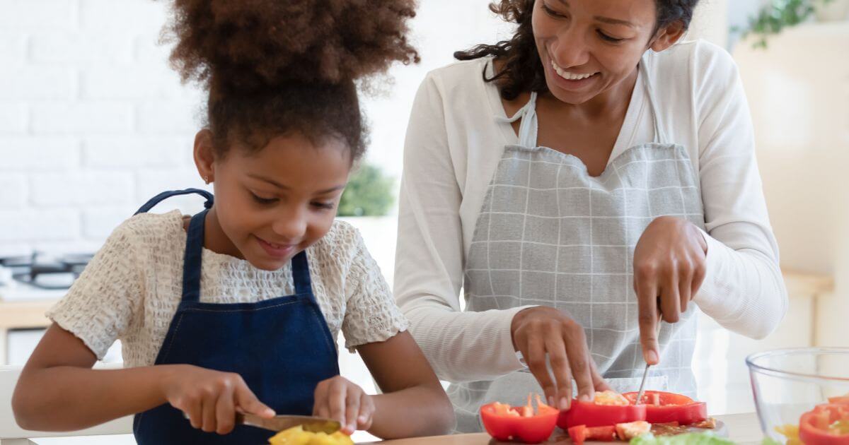 Mother and daughter preparing vegetables together in the kitchen, emphasizing healthy cooking and plant-based diet practices.