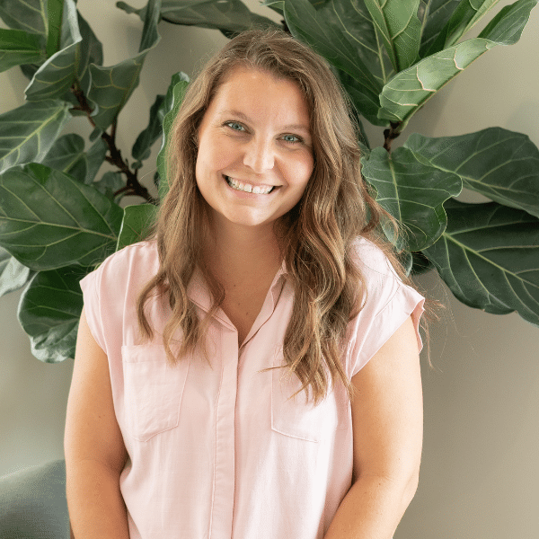 Sara, Chiropractic Assistant at Foundation Family Chiropractic, smiling in front of greenery, representing holistic health and wellness.