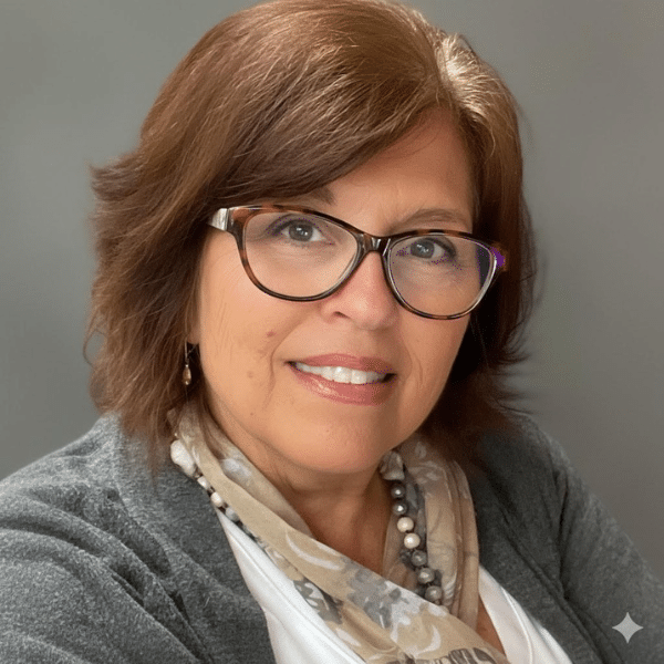 Vicki, Practice Support Manager at Foundation Family Chiropractic, smiling with glasses and a scarf, showcasing her welcoming demeanor and commitment to patient care.